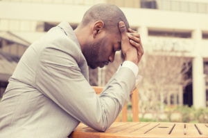 stressed businessman sitting outside corporate office